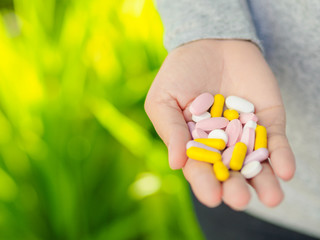 Close-up woman hand holding a lot of different pills. Health care and medical concept.