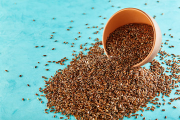 Close-up picture of flax seeds in a clay bowl isolated on blue background.