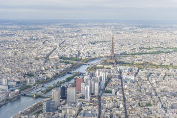Aerial view of Paris city center with the Seine river and its bridges in the foreground and the Eiffel tower in the background.