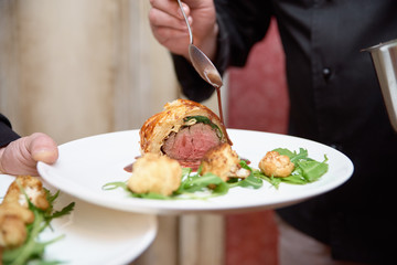a plate in the hands of the waiter. Beef tenderloin with cauliflower baked in the oven.