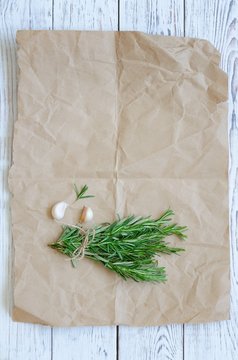 Bunch of rosemary with garlic on wrapping paper
