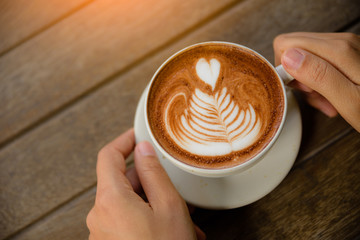 Woman hands holding cup of hot coffee latte cappuccino with heart shaped. Love, Wedding and Valentines day concept.