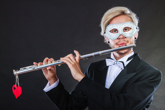 man in carnival mask playing flute