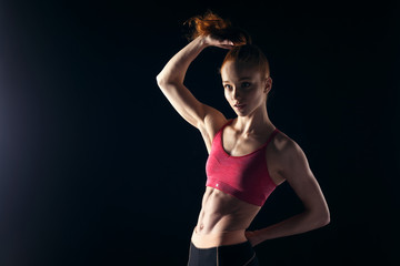 Sporty beautiful fitness trainer girl on black background
