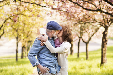 Senior couple in love outside in spring nature kissing.