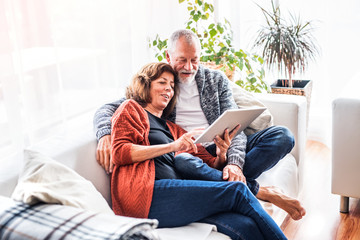 Senior couple with tablet relaxing at home.