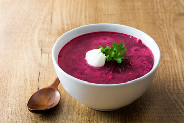 Beet soup in white bowl on wooden table