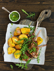 Chops of lamb on bone, with baked potatoes and pesto sauce.