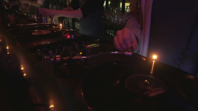 cool dj behind the turntables performing in a bar