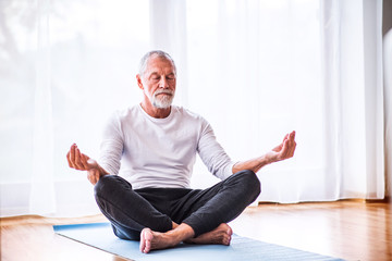 Senior man meditating at home. - Powered by Adobe