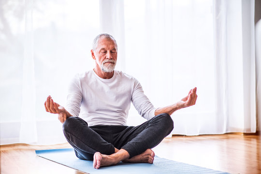 Senior Man Meditating At Home.