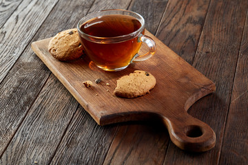 Cup of tea with cookies on a cutting board on a wooden background, top view
