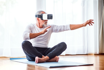 Senior man with VR goggles doing exercise at home.