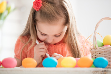 Fototapeta na wymiar Focused child creating drawings on colorful dyed eggs