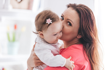 Mother kissing her baby daughter.