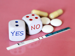 Pregnancy test positive with two stripes and contraceptive pill. The dice on pink background.