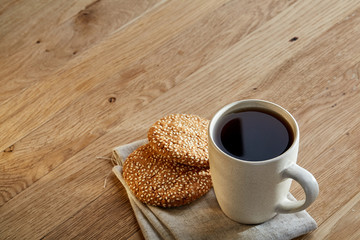 Porcelain teacup with chocolate chips cookies on cotton napkin on a rustic wooden background, top view