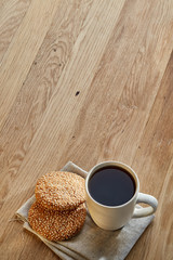 Porcelain teacup with chocolate chips cookies on cotton napkin on a rustic wooden background, top view