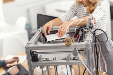 Best result. The focus being on the delicate hands of a young woman removing a model from the 3D printer, having just printed it, and being about to use it in her project