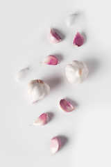Falling Garlic bulbs and pink cloves of garlic isolated on white background