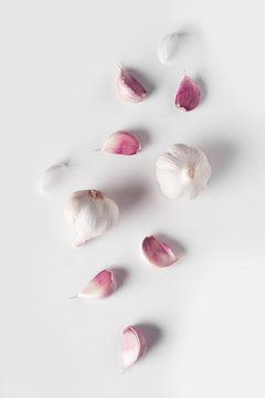 Falling Garlic bulbs and pink cloves of garlic isolated on white background