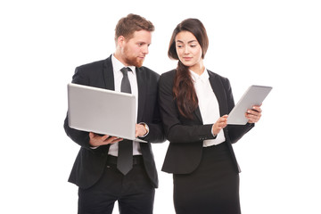 Studio portrait of Asian businesswoman and Caucasian businessman holding laptop and tablet computer