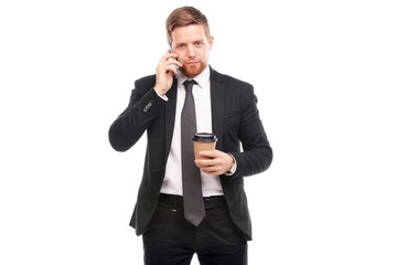 Portrait of young businessman holding paper coffee cup and using cell phone