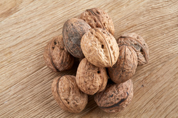 A stack of walnuts piled together and on rustic wooden background, shallow depth of field, selective focus