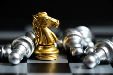Gold horse in chess game face with the another silver team on black background (Concept for company...