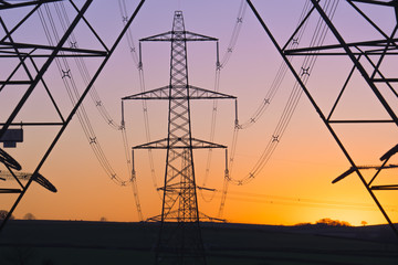 An electricity pylon of the National Grid in Wales at sunset. - obrazy, fototapety, plakaty