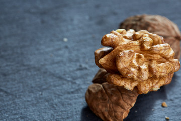 Top view close-up shot of cracked walnuts on dark background, shallow depth of field, macro