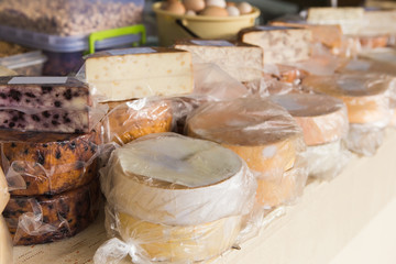 The farm food market. A lot of cheeses on the sales counter.