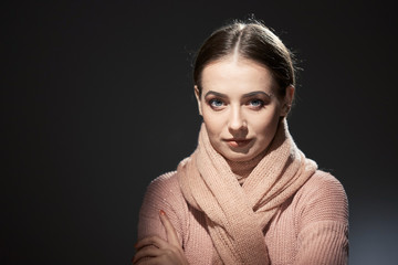beautiful girl in pink knitted sweater. emotional portrait on a dark background.