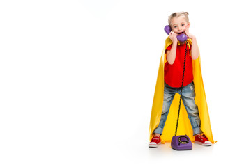 Shocked little supergirl wearing yellow cape and talking on phone isolated on white