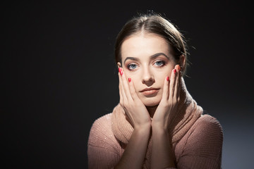 beautiful girl in pink knitted sweater. emotional portrait on a dark background.