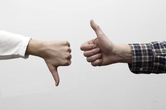 Two hands signalling thumbs up and thumbs down. The smooth hand on the left is making a thumbs up gesture while the hairy hand on the right is making a thumbs down gesture.