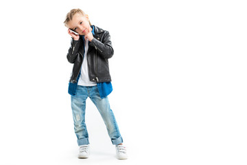 View of kid talking on smartphone and holding finger on chin isolated on white