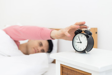 Man sleeping in bed early wake up not getting enough sleep feel irritated when they hear the alarm clock