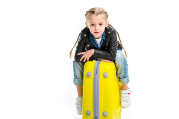 View of kid with pigtails sitting on yellow wheel suitcase isolated on white