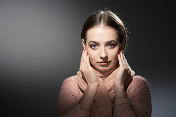 beautiful girl in pink knitted sweater. emotional portrait on a dark background.