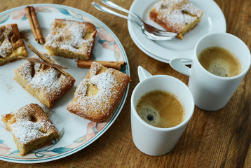 Coffee mug with apple cinnamon cake pieces on wooden table