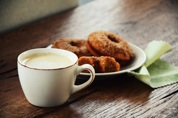 Cup of coffee with pumpkin spice whole wheat doughnuts on wooden table