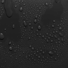 Surface with water drops, dark background.