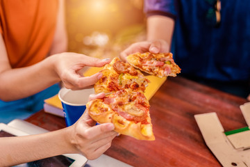 People celebrating with pizza in hand. Food and Friendship concept. Lifestyles theme