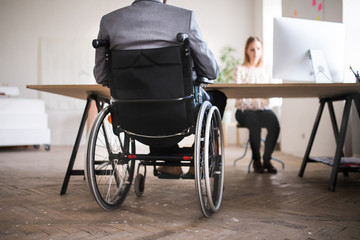 Fototapeta na wymiar Two business people with wheelchair in the office.