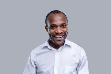Wonderful day. Handsome happy dark-eyed afro-american man wearing a white shirt and smiling and having delighted expression