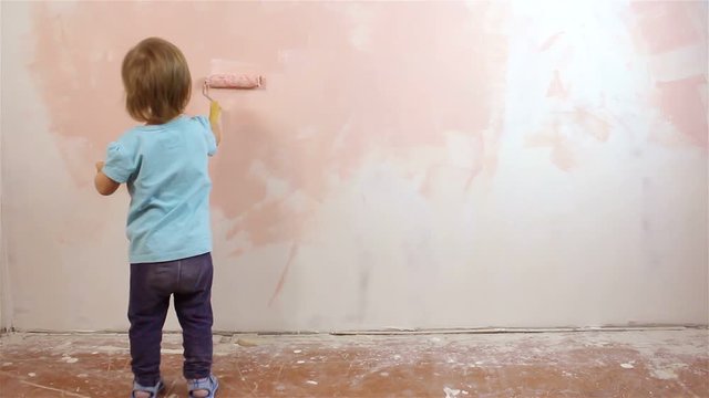 Happy little baby painting the wall