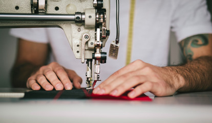 Close-up man hands sewing fabric on sewing machine