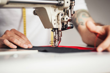 Close-up man hands sewing fabric on sewing machine