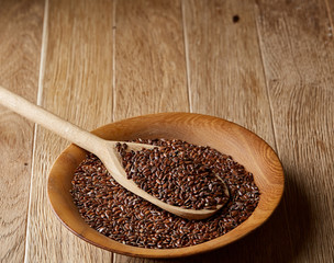Wooden spoon with flax seeds on rustic background, top view, close-up, shallow depth of field, selective focus
